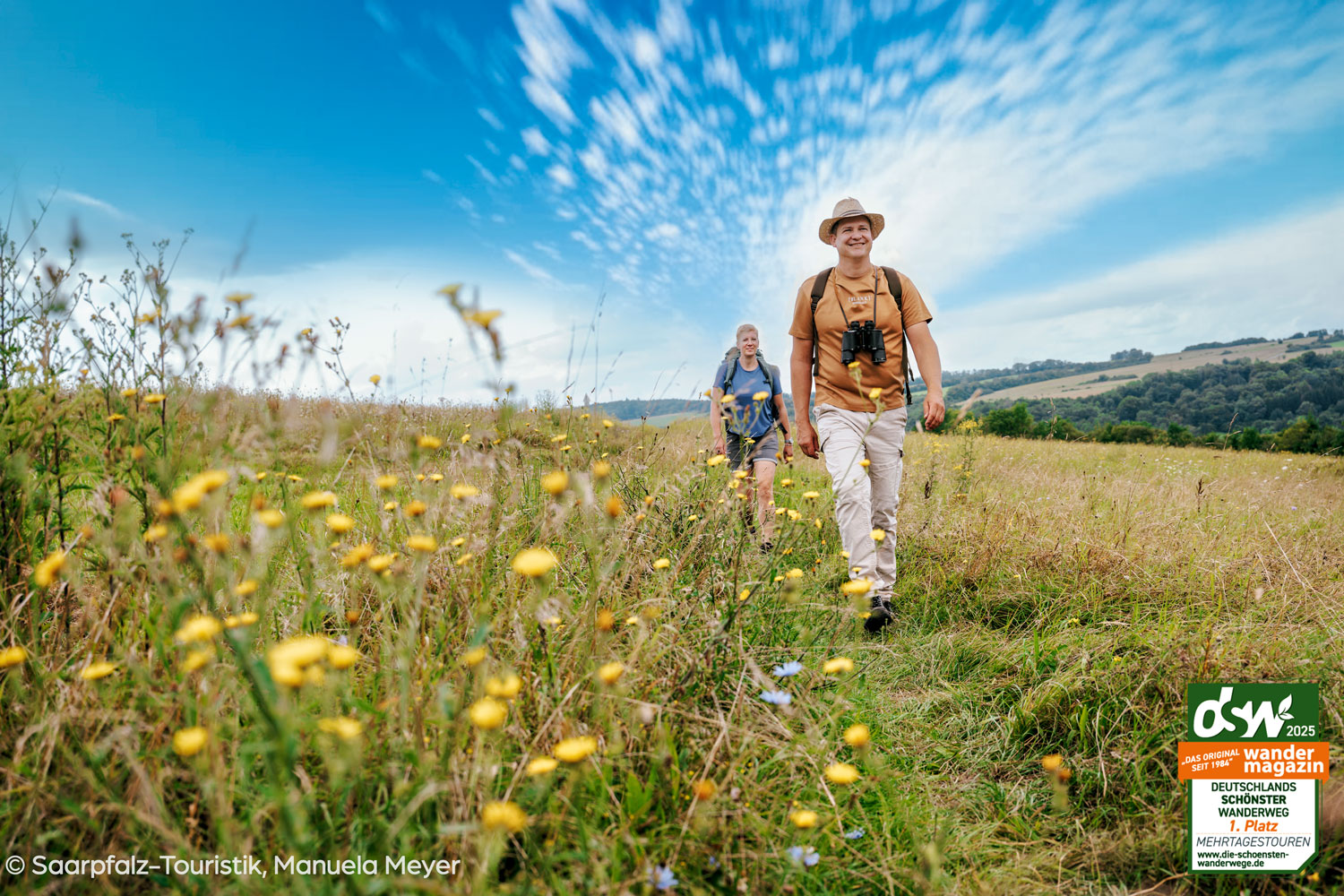 Zwei Wanderer streifen durch die Blumenwiese auf dem Bliessteig
